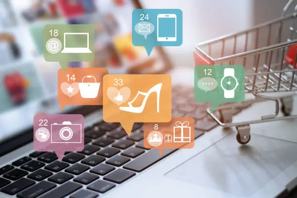Price products for an online store: laptop with mini shopping cart and floating icons for shoes, bags, watch and phone