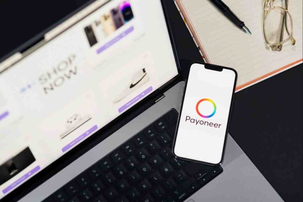 Best Payment Gateways Online Store: Payoneer app on a smartphone resting on a laptop showing a shop page