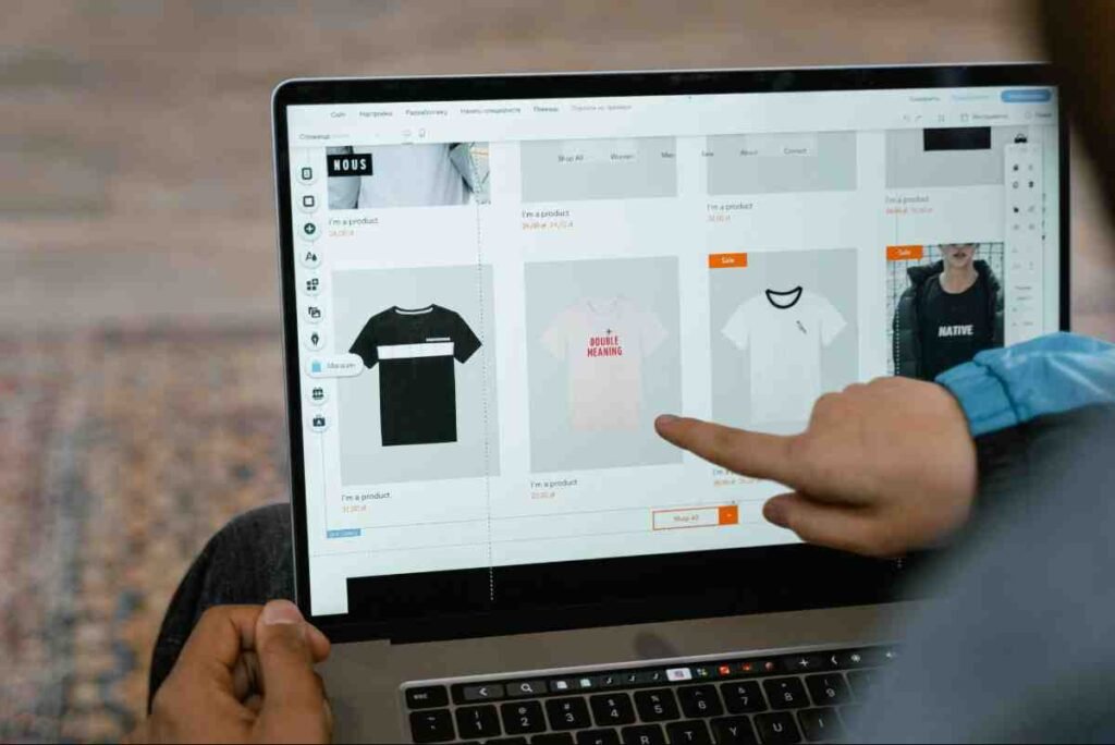 Shopify vs Etsy: person pointing at t-shirt products in an online store builder on a laptop screen