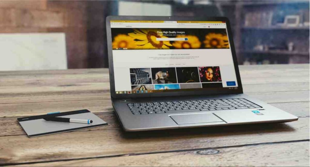 Laptop showing a free stock photo website beside a pen tablet, image tips from a WordPress SEO setup guide