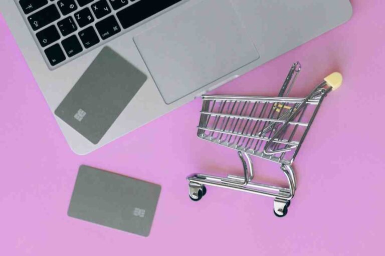 Ecommerce Store Case Study concept with a laptop, credit cards and a mini shopping cart on a pink background