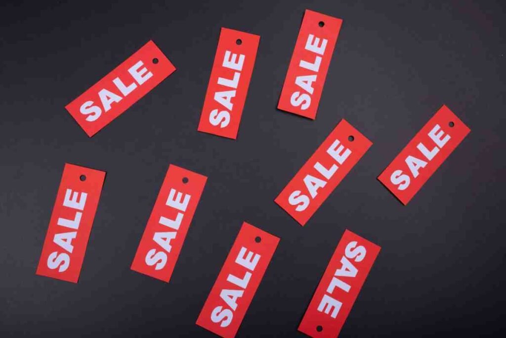 Reasons Shopify Stores Fail: red SALE tags scattered on a black background