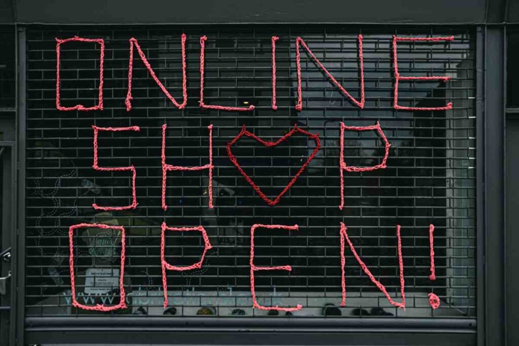 Price products for an online store: pink yarn letters spelling 'Online Shop Open!' on a black shop shutter